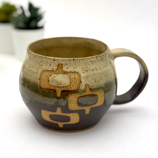 Handmade ceramic mug with a rounded shape, finished in two glazes with a mid-century–inspired pattern in earthy tones.