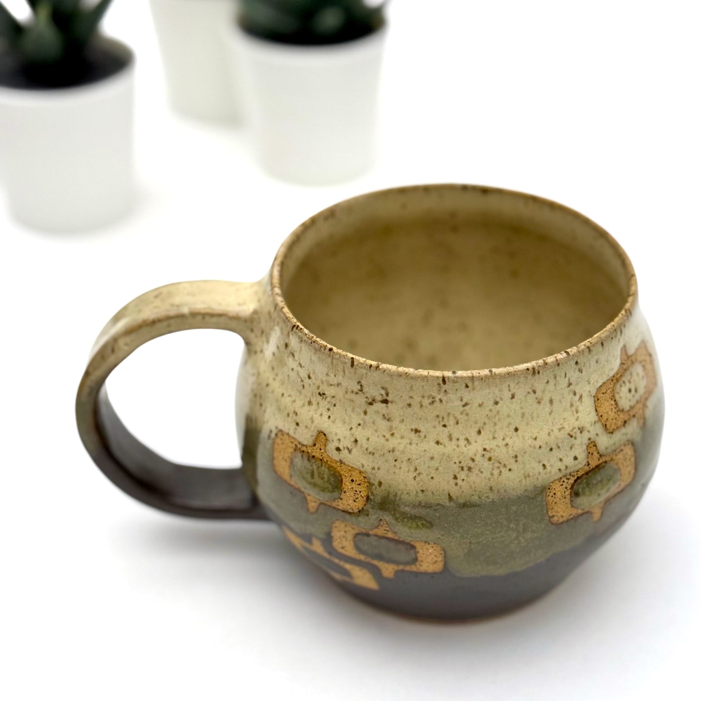 Handmade ceramic mug with a rounded shape, finished in two glazes with a mid-century–inspired pattern in earthy tones.