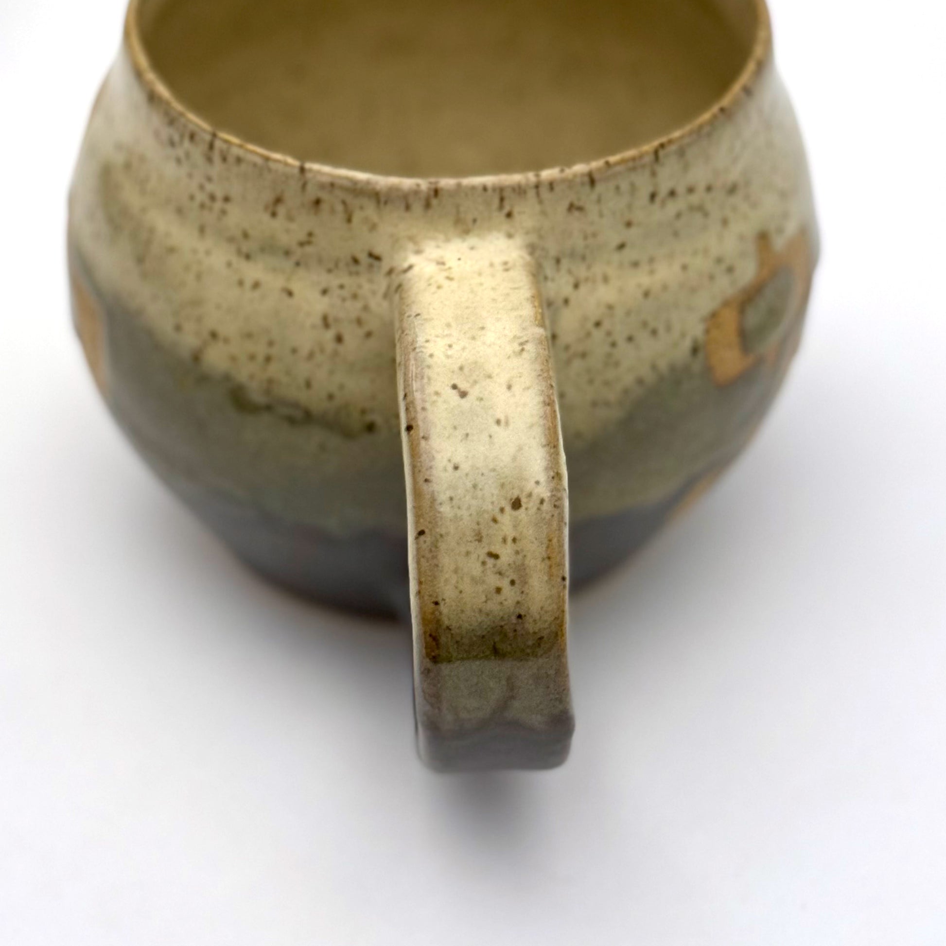 Handmade ceramic mug with a rounded shape, finished in two glazes with a mid-century–inspired pattern in earthy tones.