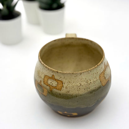 Handmade ceramic mug with a rounded shape, finished in two glazes with a mid-century–inspired pattern in earthy tones.