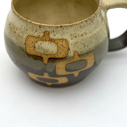 Handmade ceramic mug with a rounded shape, finished in two glazes with a mid-century–inspired pattern in earthy tones.