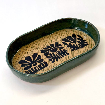 Ceramic dish with black floral patterns on a beige background