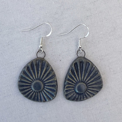 Pair of earrings with sunburst design on a light gray background
