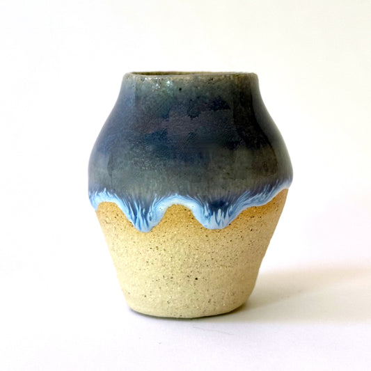 Small speckled stoneware bud vase with a deep navy glaze that drips into a frothy sky-blue wave over a raw, sandy clay base