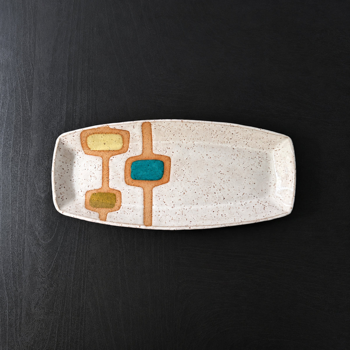 Handmade rectangular ceramic tray with softly rounded corners, finished in a glossy white glaze with exposed speckled clay forming mid-century geometric designs. Accents of turquoise blue, mustard yellow, and olive green add pops of color.