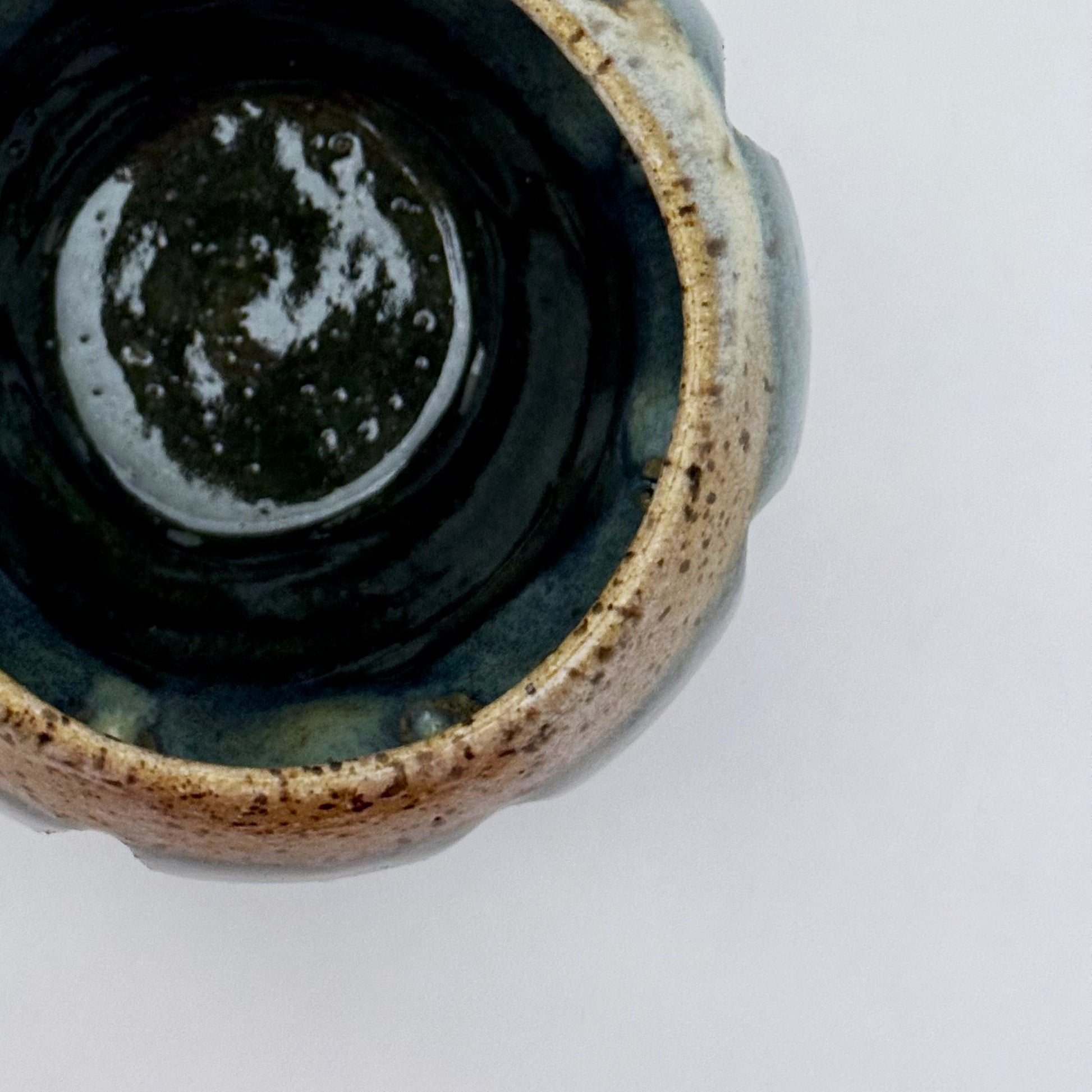 Top view of ceramic luminary with teal glaze and vertical cutouts.