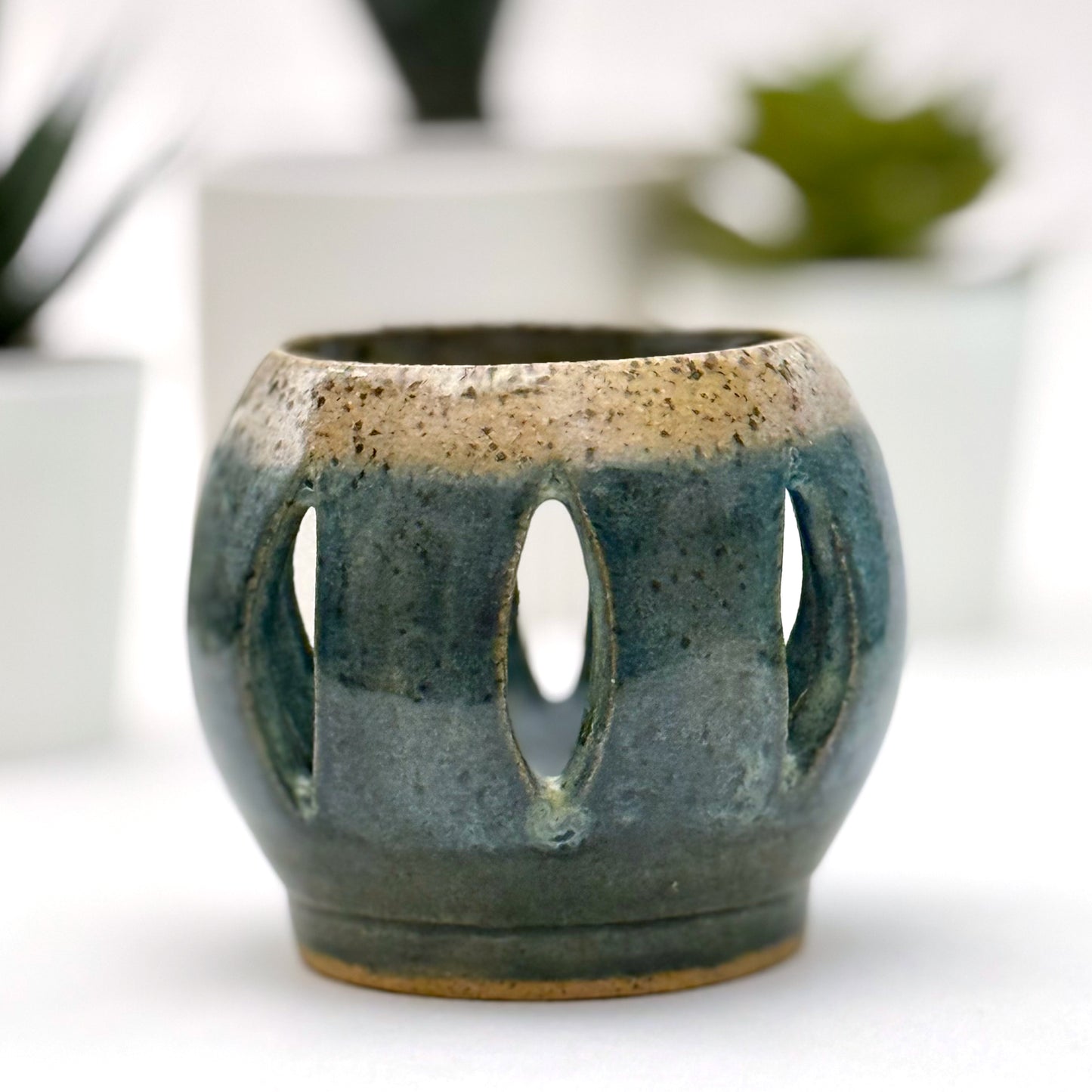 Ceramic luminary with teal glaze and vertical cutouts.