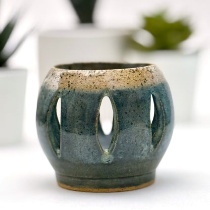 Ceramic luminary with teal glaze and vertical cutouts.