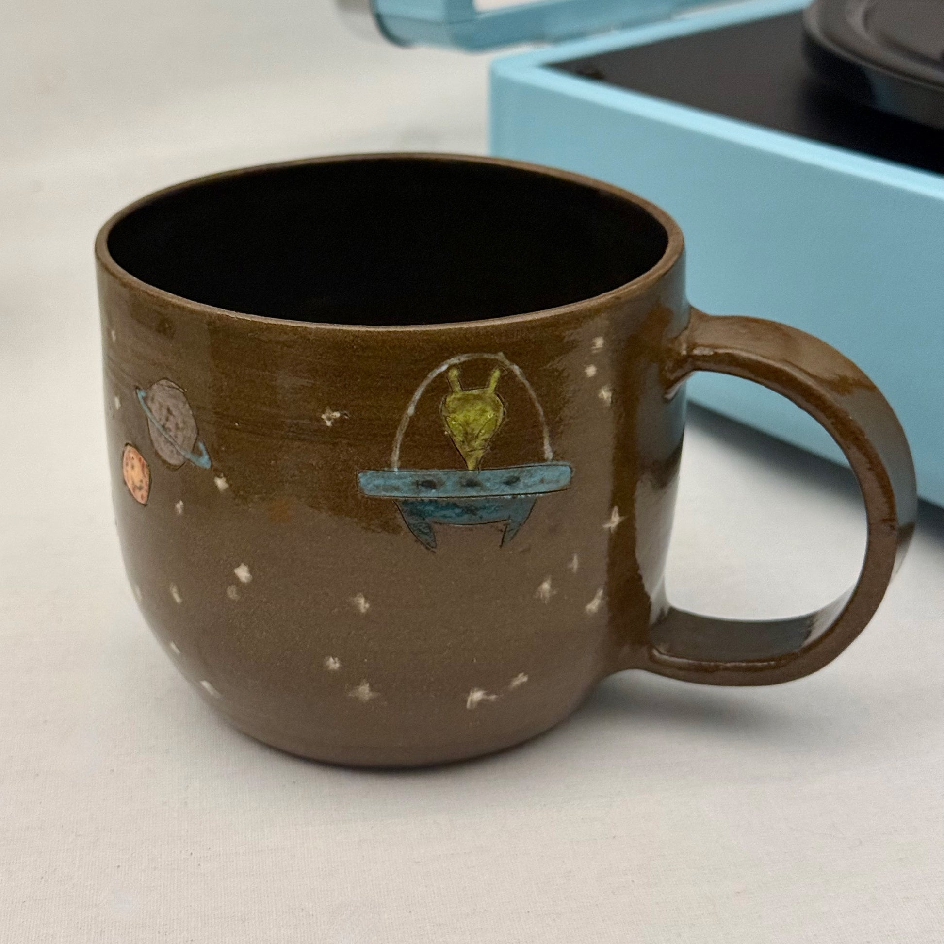 Ceramic mug with space-themed design on a light surface