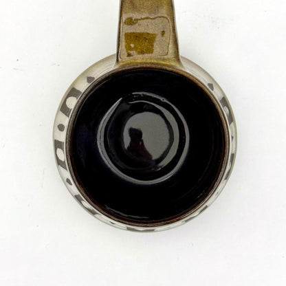 Top view of a handmade ceramic mug with a bold mid-century–inspired vertical tape-resist pattern.