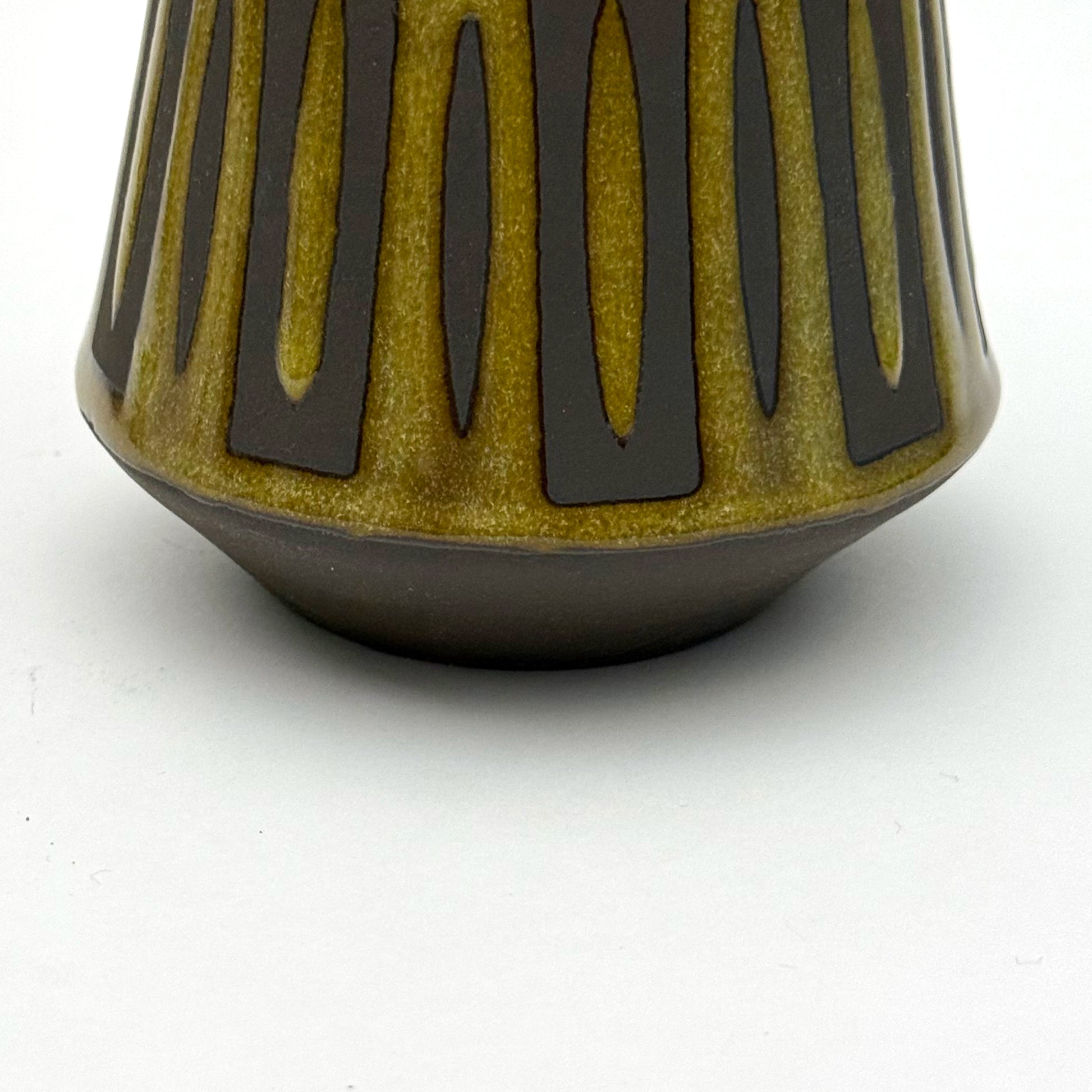Close up of handmade ceramic mug finished in Curry glaze with a bold mid-century–inspired vertical tape-resist pattern.