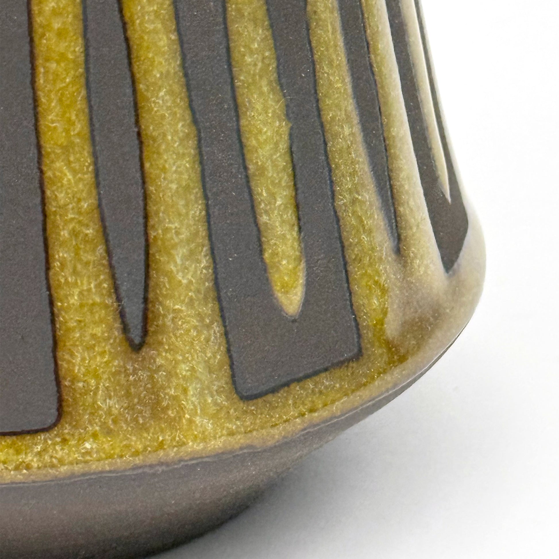 Close up of handmade ceramic mug finished in Curry glaze with a bold mid-century–inspired vertical tape-resist pattern.