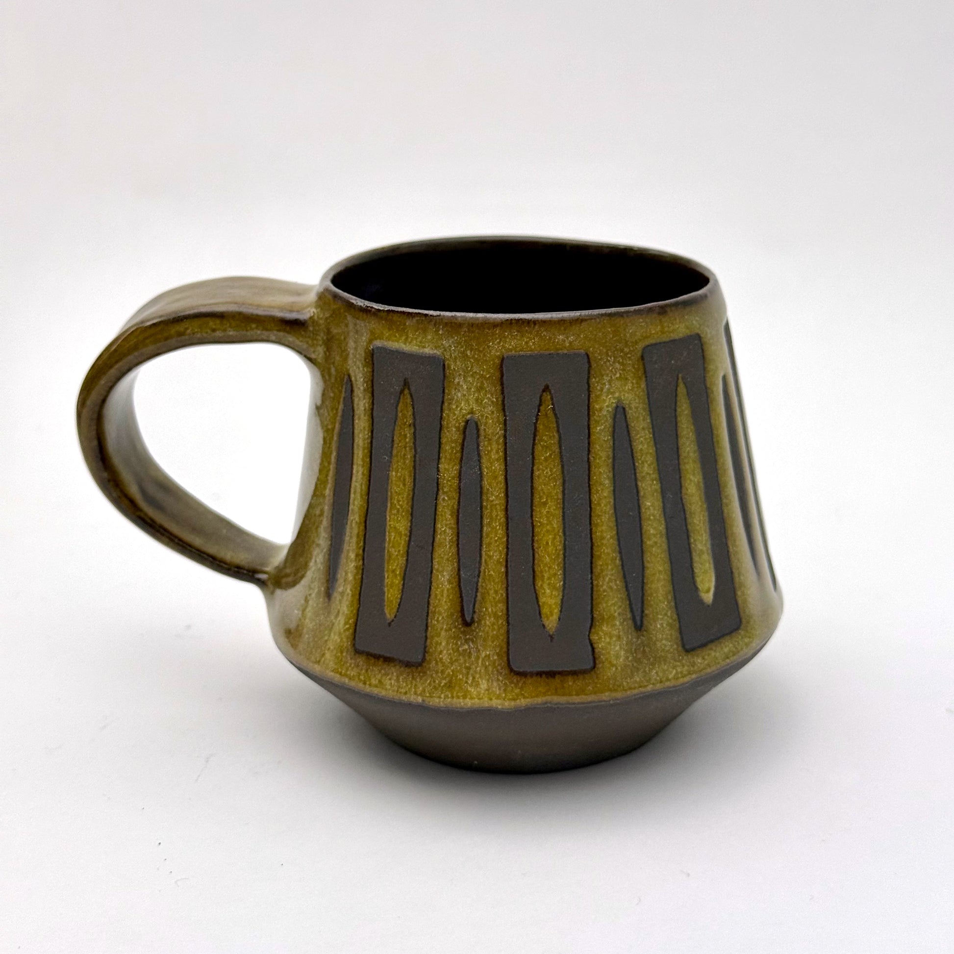 Handmade ceramic mug with a bold mid-century–inspired vertical tape-resist pattern.