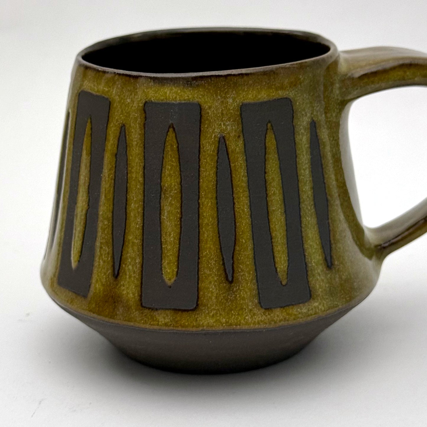 Handmade ceramic mug with a bold mid-century–inspired vertical tape-resist pattern.