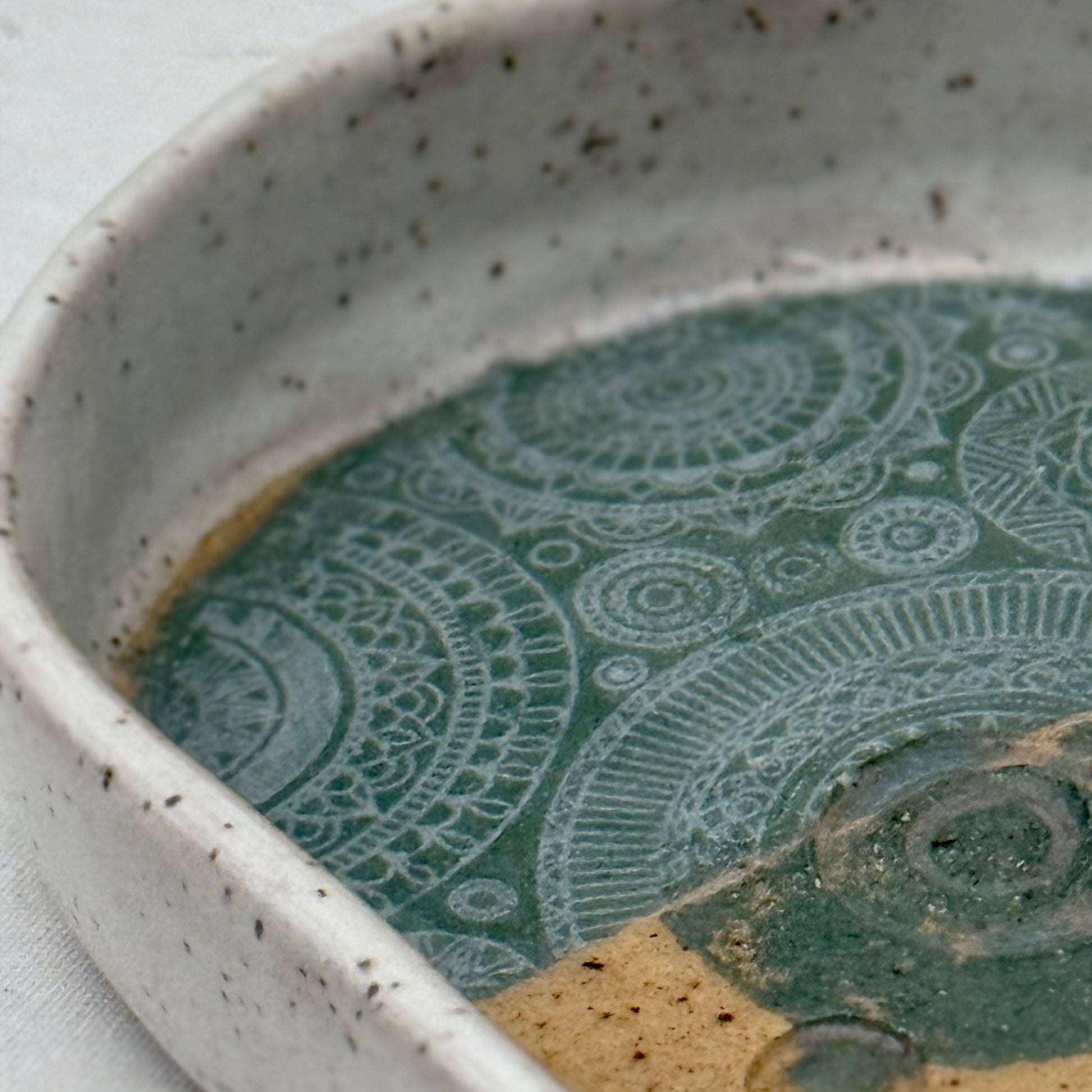 Ceramic dish with green patterned interior and speckled exterior