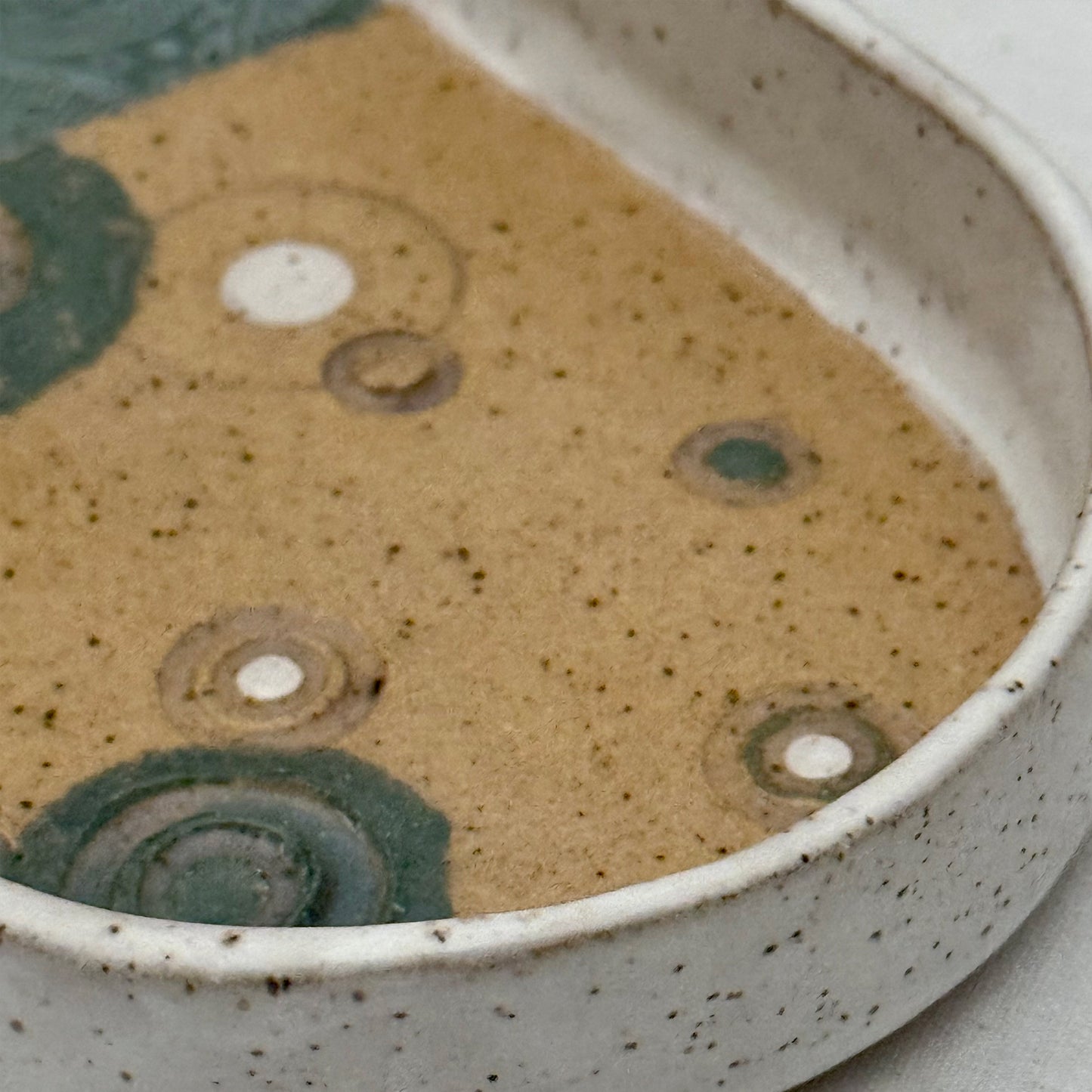 Close-up of a ceramic bowl with speckled glaze and circular patterns.