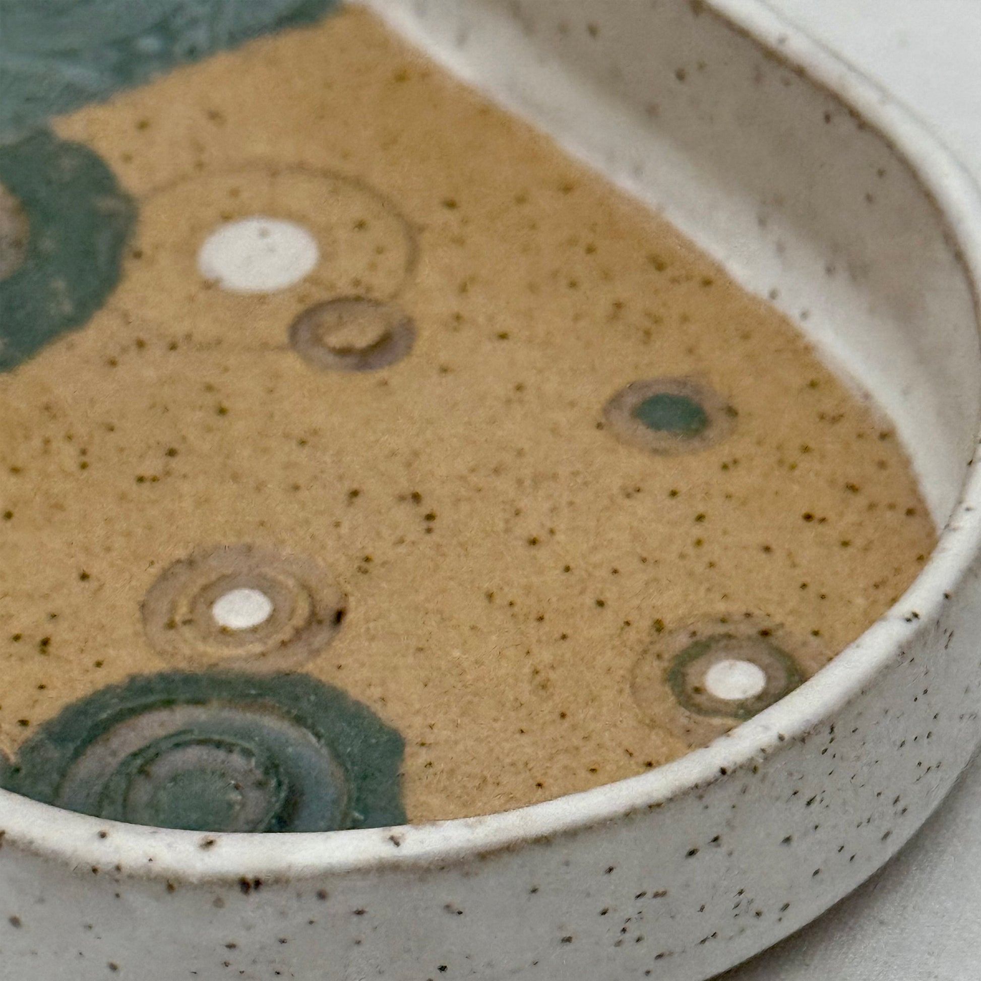 Close-up of a ceramic bowl with speckled glaze and circular patterns.