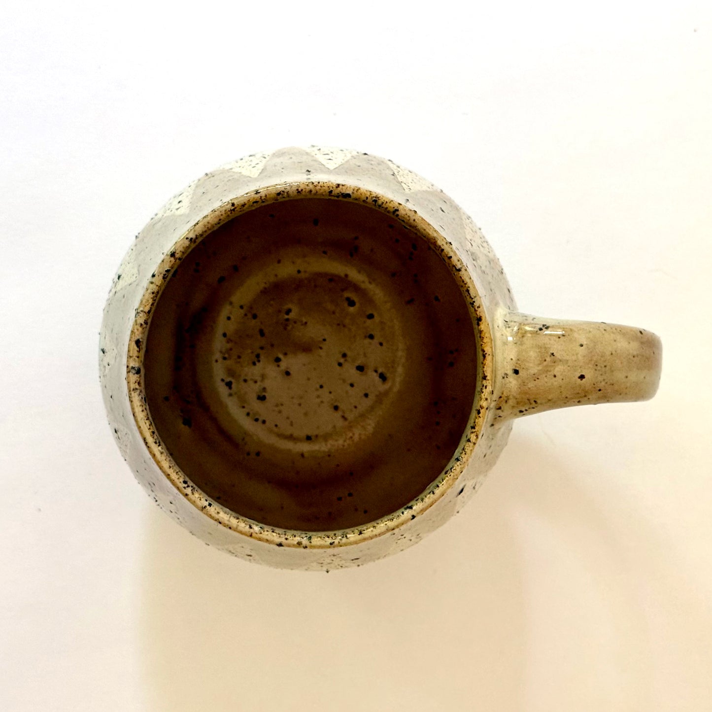 Ceramic mug with speckled design on a beige background