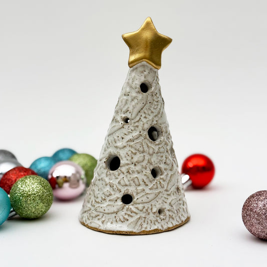 Decorative ceramic Christmas tree luminary with a gold star on top, surrounded by colorful ornaments.
