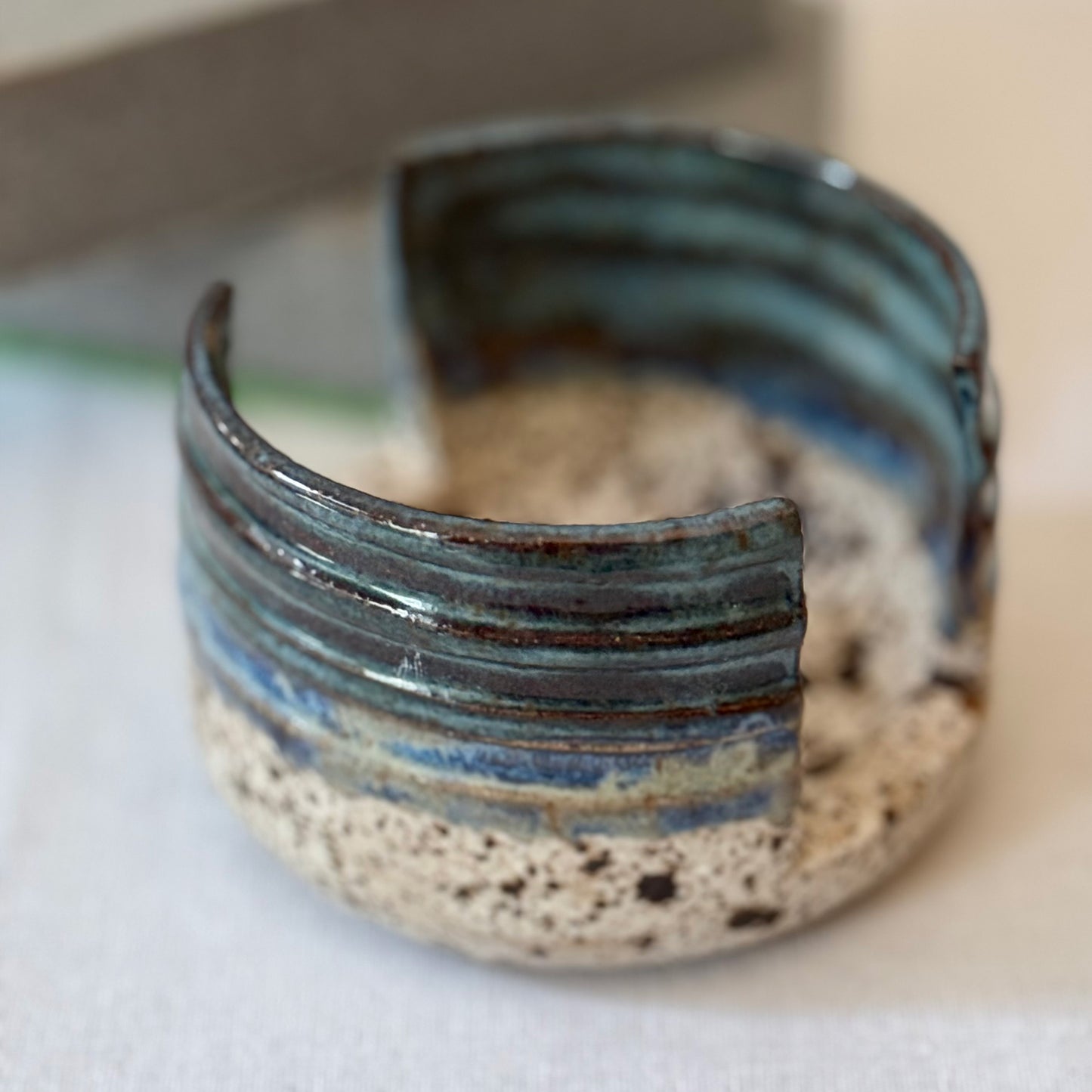 Ceramic sponge holder with blue and brown glaze on a white surface