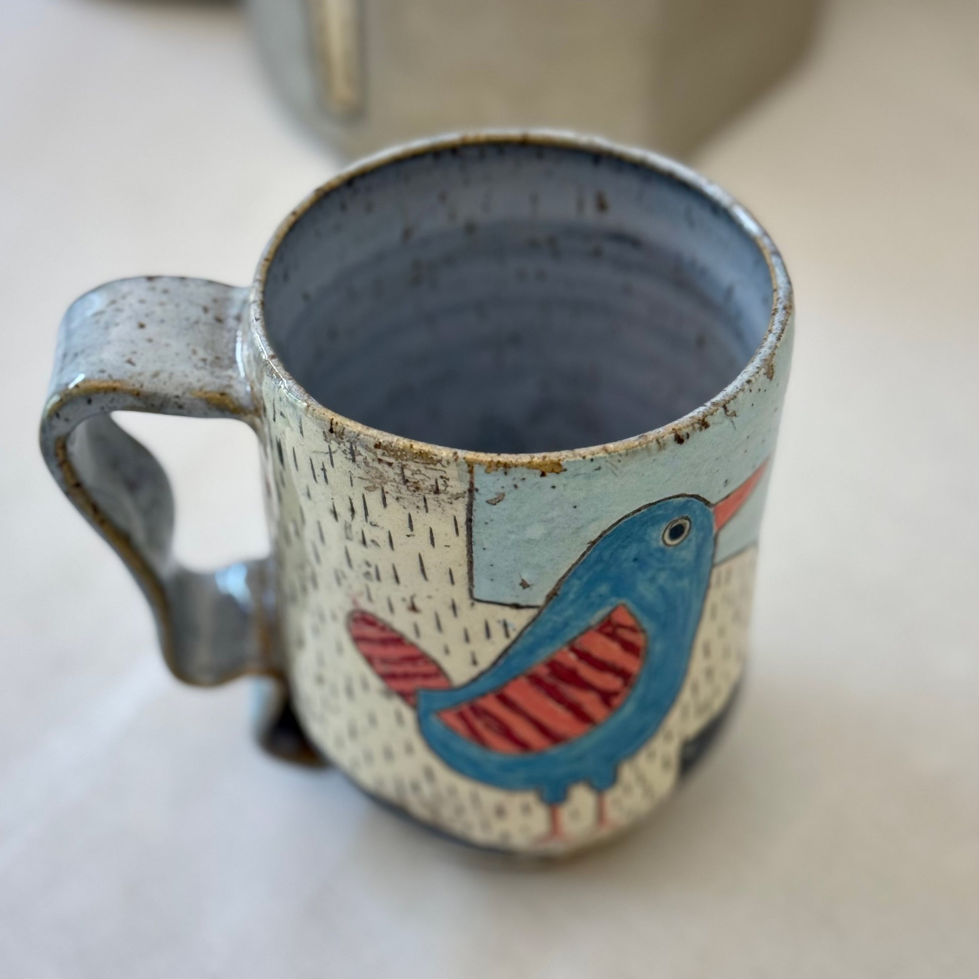 Ceramic mug with a bird design on a white surface