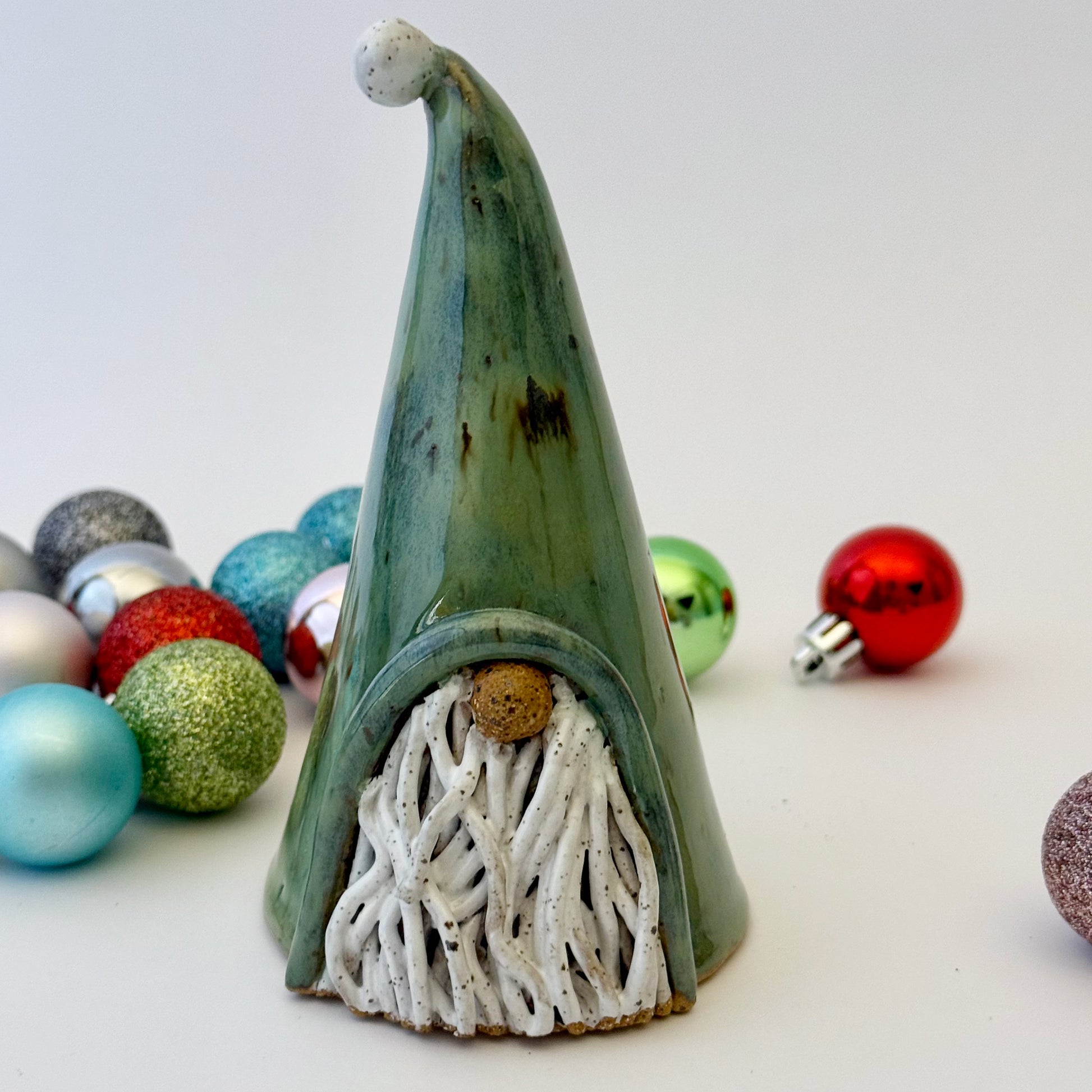 green ceramic gnome with ornaments on white background