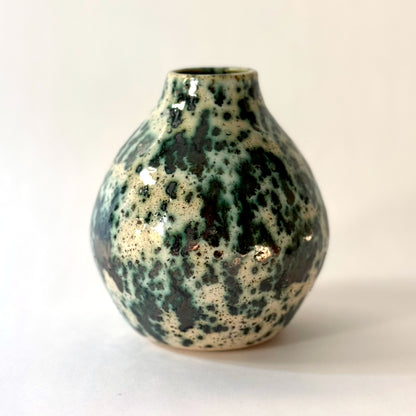 Small handmade pottery vase with a rounded shape and narrow opening, finished in a green jasper glaze with varied green tones and irregular speckled patterning across the surface.
