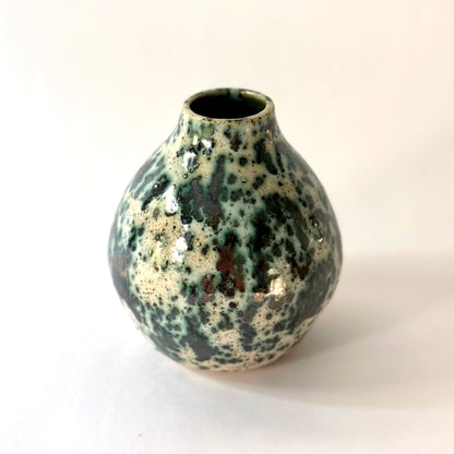 Small handmade pottery vase with a rounded shape and narrow opening, finished in a green jasper glaze with varied green tones and irregular speckled patterning across the surface.