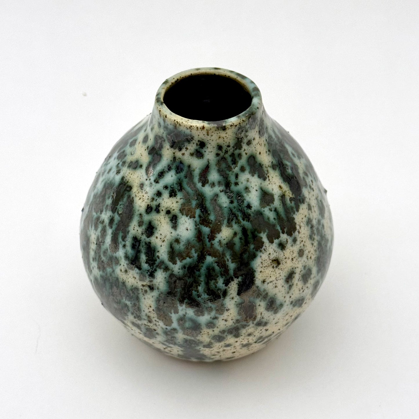 Small handmade pottery vase with a rounded shape and narrow opening, finished in a green jasper glaze with varied green tones and irregular speckled patterning across the surface.