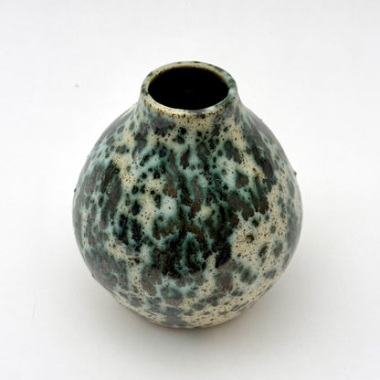 Small handmade pottery vase with a rounded shape and narrow opening, finished in a green jasper glaze with varied green tones and irregular speckled patterning across the surface.