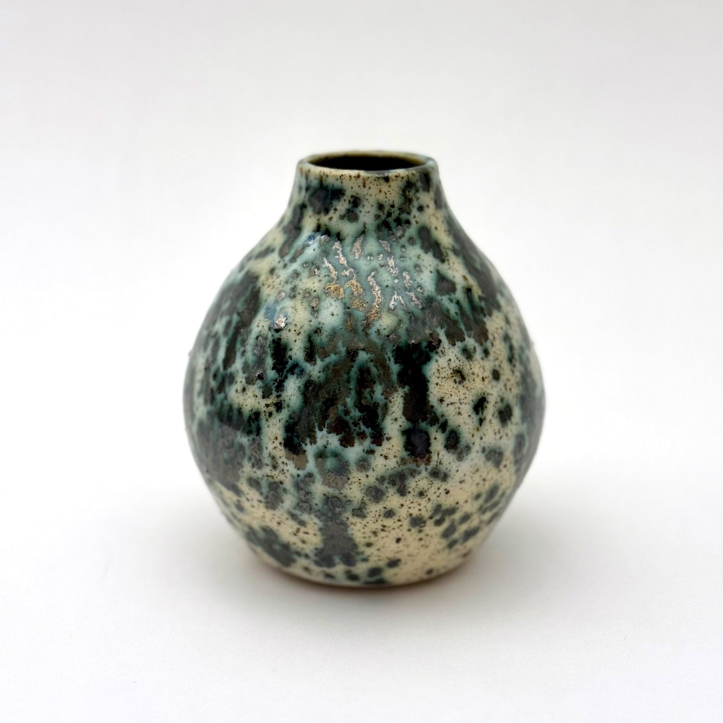 Small handmade pottery vase with a rounded shape and narrow opening, finished in a green jasper glaze with varied green tones and irregular speckled patterning across the surface.