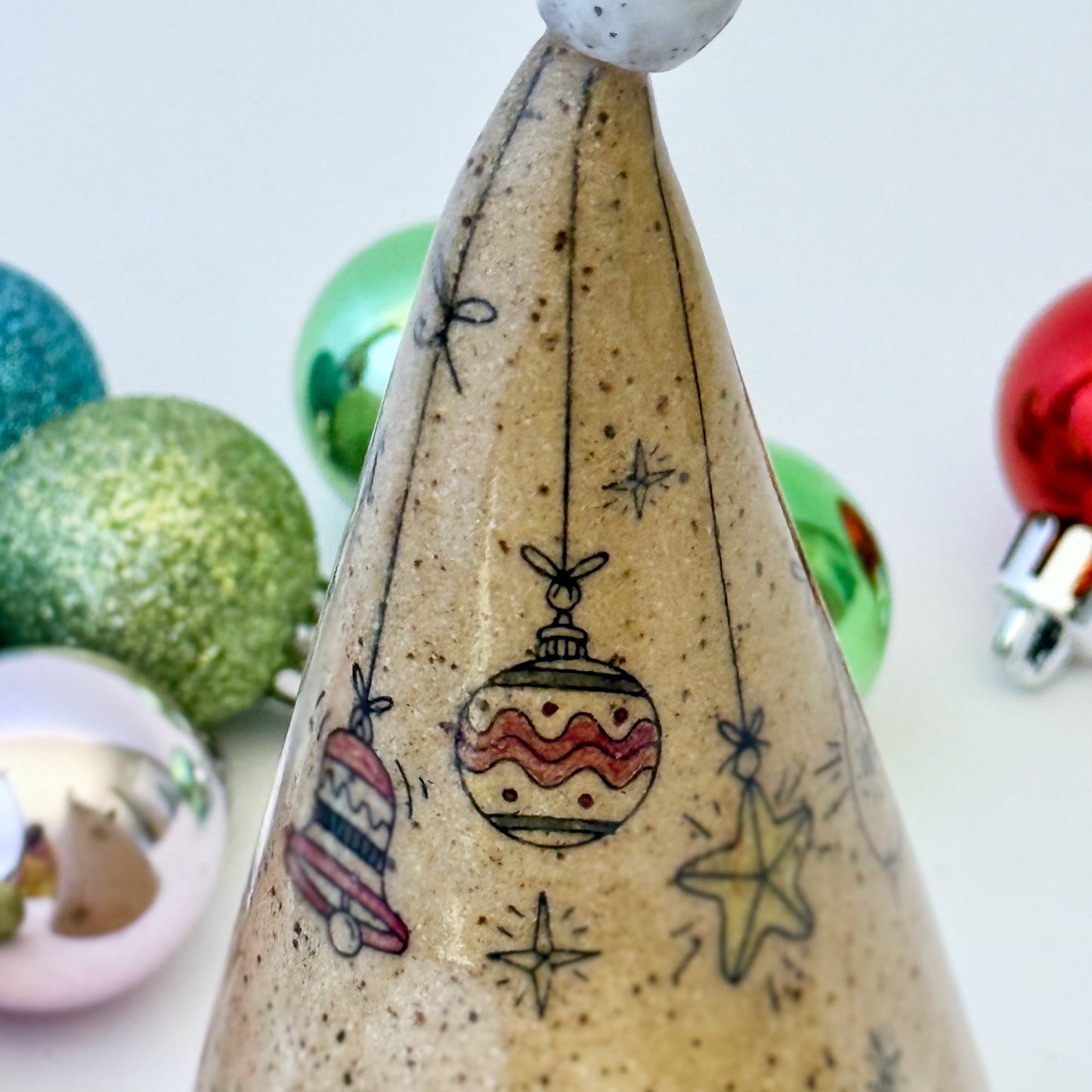 close-up of ceramic gnome with braids and red bows with ornaments on a white background 
