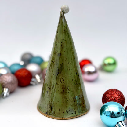 Back view of a ceramic gnome luminary with a green hat, star-shaped window, speckled white beard, and round nose, styled with Christmas ornaments.
