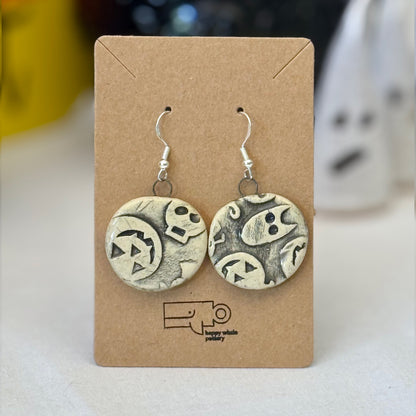 Pair of black halloween themed ceramic earrings on a brown card with a blurred background
