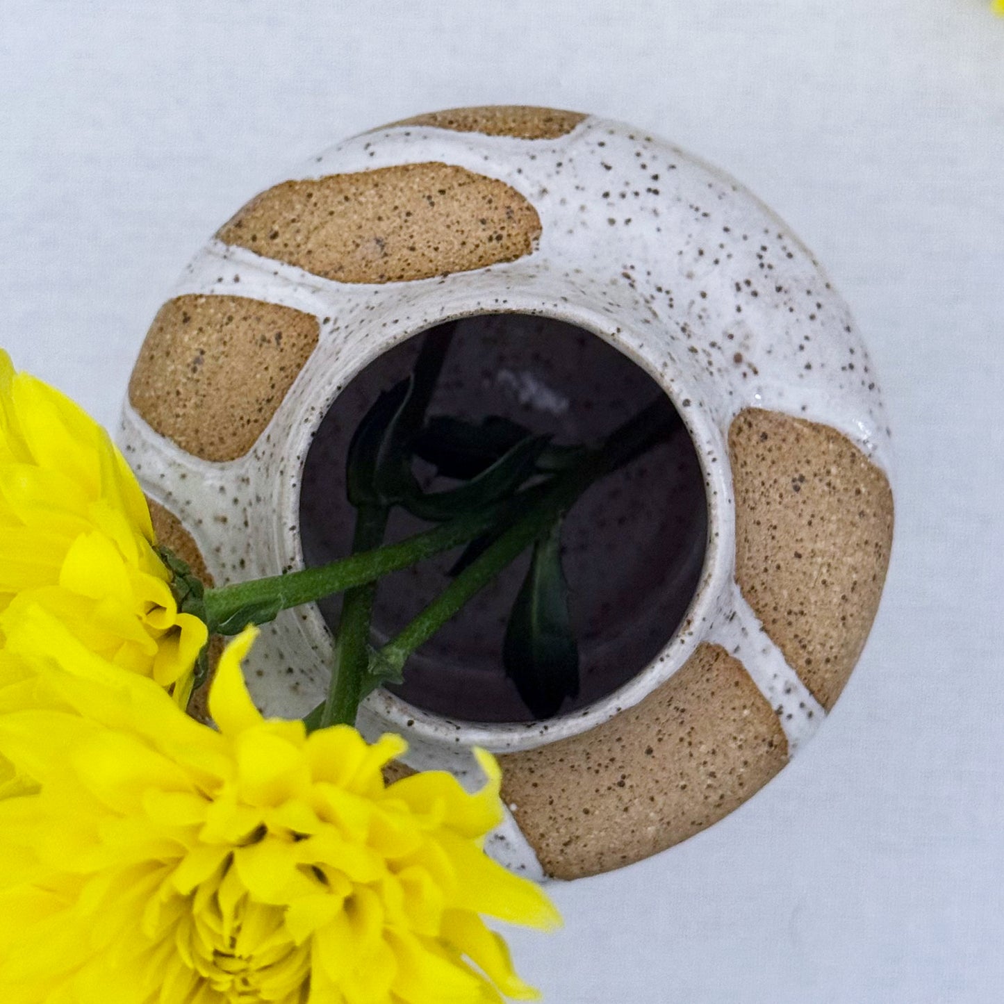 Speckled ceramic vase with yellow flowers on a light background