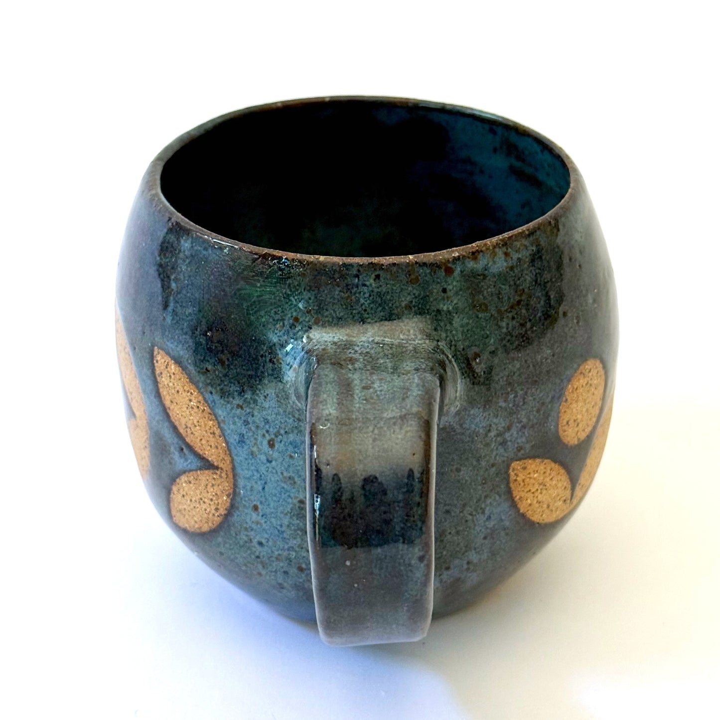Ceramic mug with a rounded shape and handle, featuring an isometric geometric pattern revealed through a deep blue glaze.