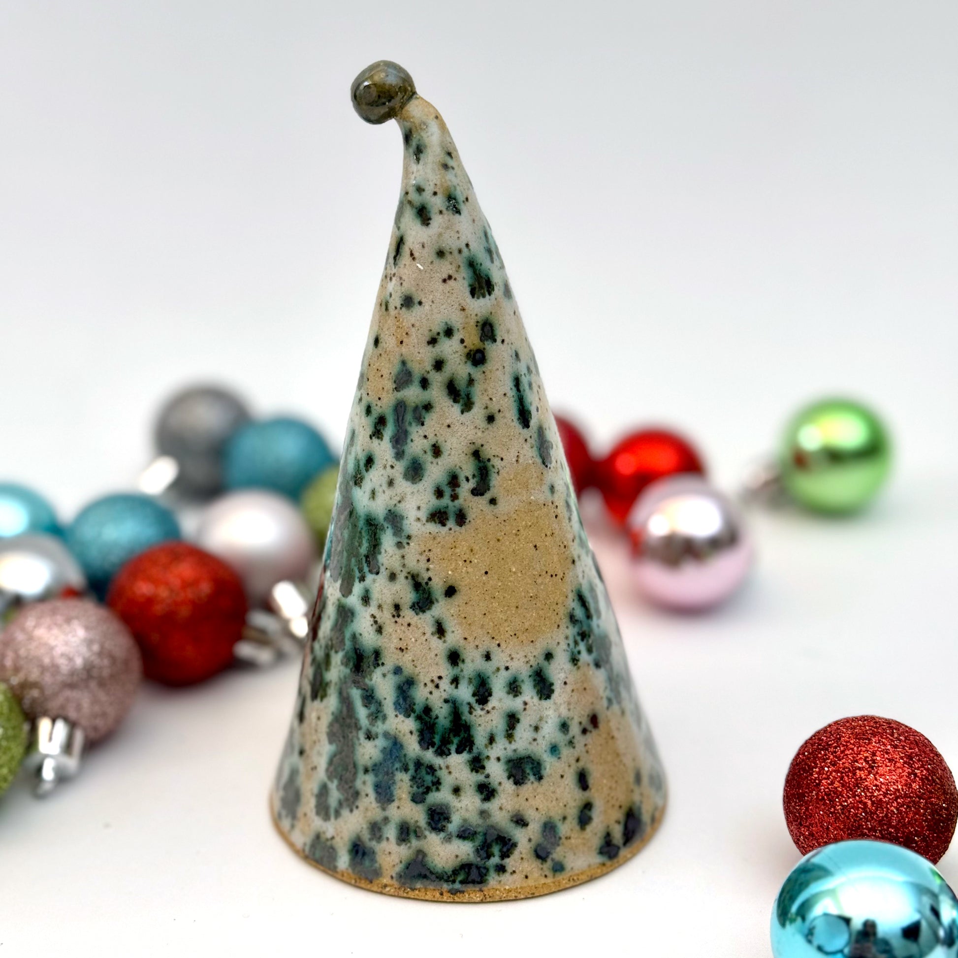 Back view of a decorative gnome figure with a speckled hat surrounded by colorful ornaments on a white background