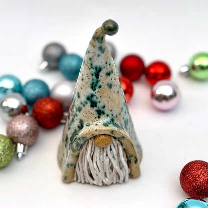 Decorative gnome figure with a speckled hat surrounded by colorful ornaments on a white background