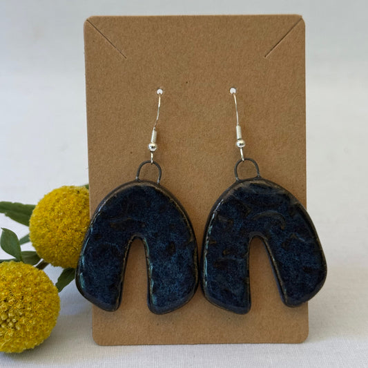 dark blue ceramic earrings on brown card