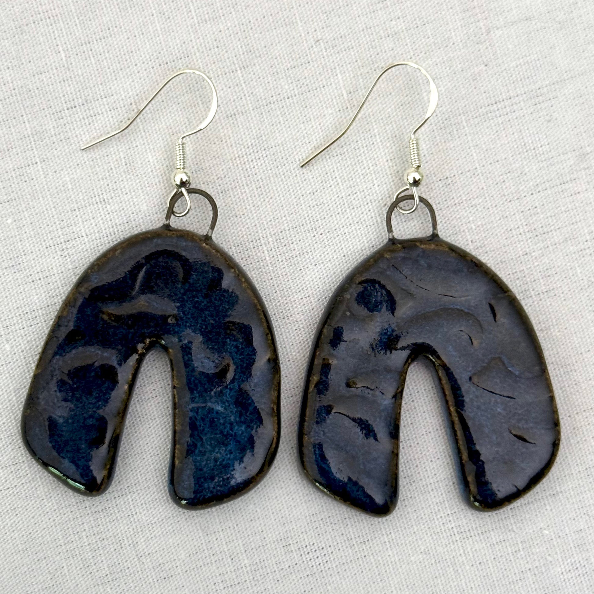 Pair of dark blue ceramic earrings on a light background