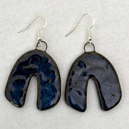 Pair of dark blue ceramic earrings on a light background