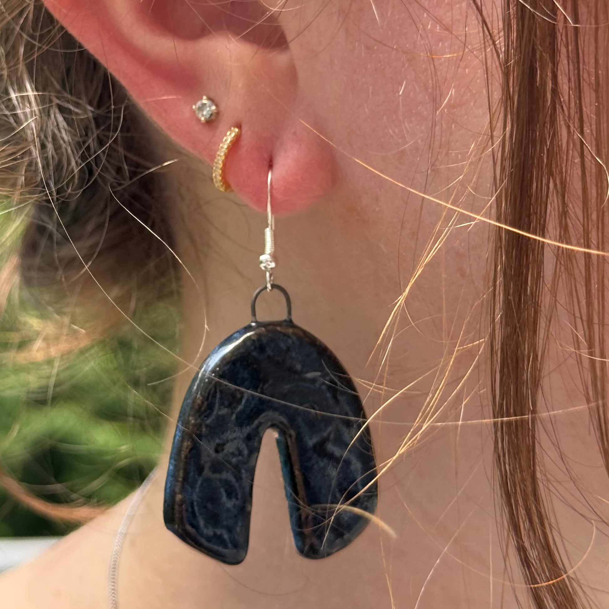 Close-up of a person wearing a blue textured earring with a blurred background