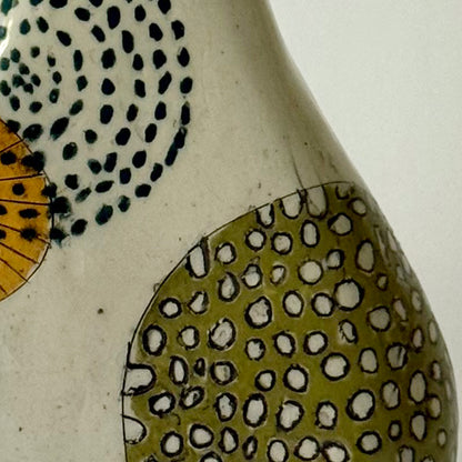 Close up of handbuilt speckled stoneware vase with colorful mid-century-inspired monoprints featuring graphic florals, dotted orbits, and botanical motifs, finished in a glossy clear glaze