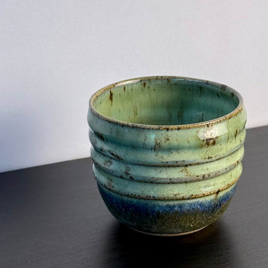 Small handmade Olive Groove Pot with a rounded shape, carved horizontal bands, and glossy olive-green glaze that shifts to deep blue-green and earthy brown near the base.