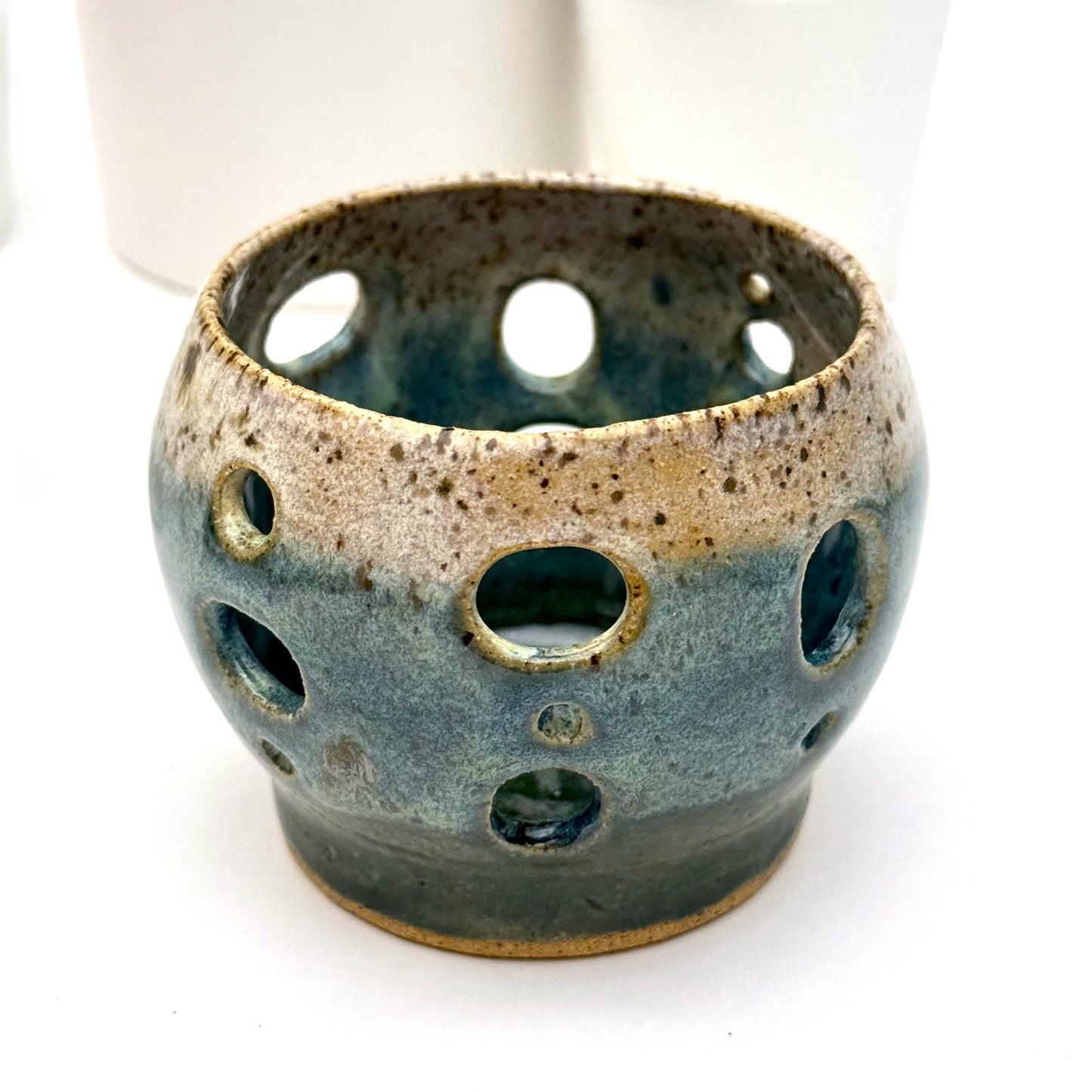 Handmade ceramic luminary with a deep teal glaze and oval cutout openings.