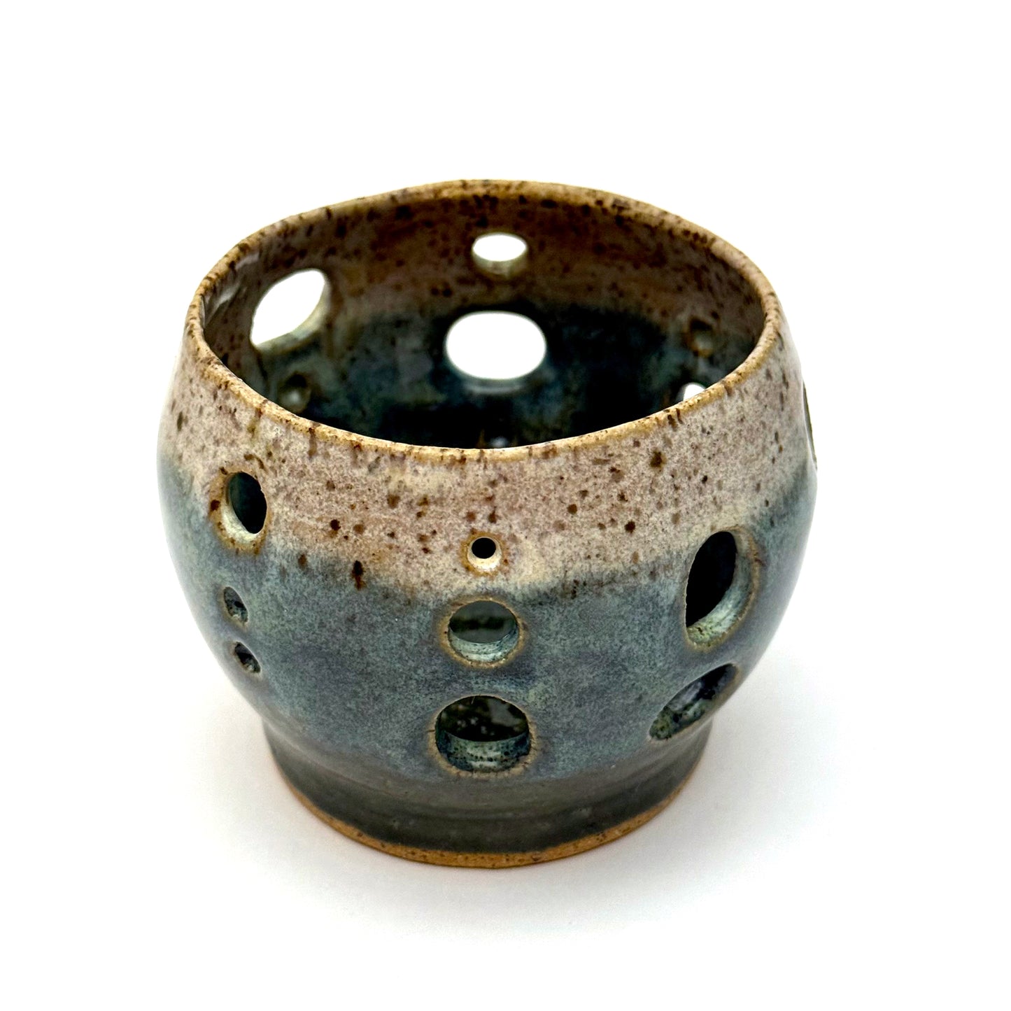 Handmade ceramic luminary with a deep teal glaze and oval cutout openings.