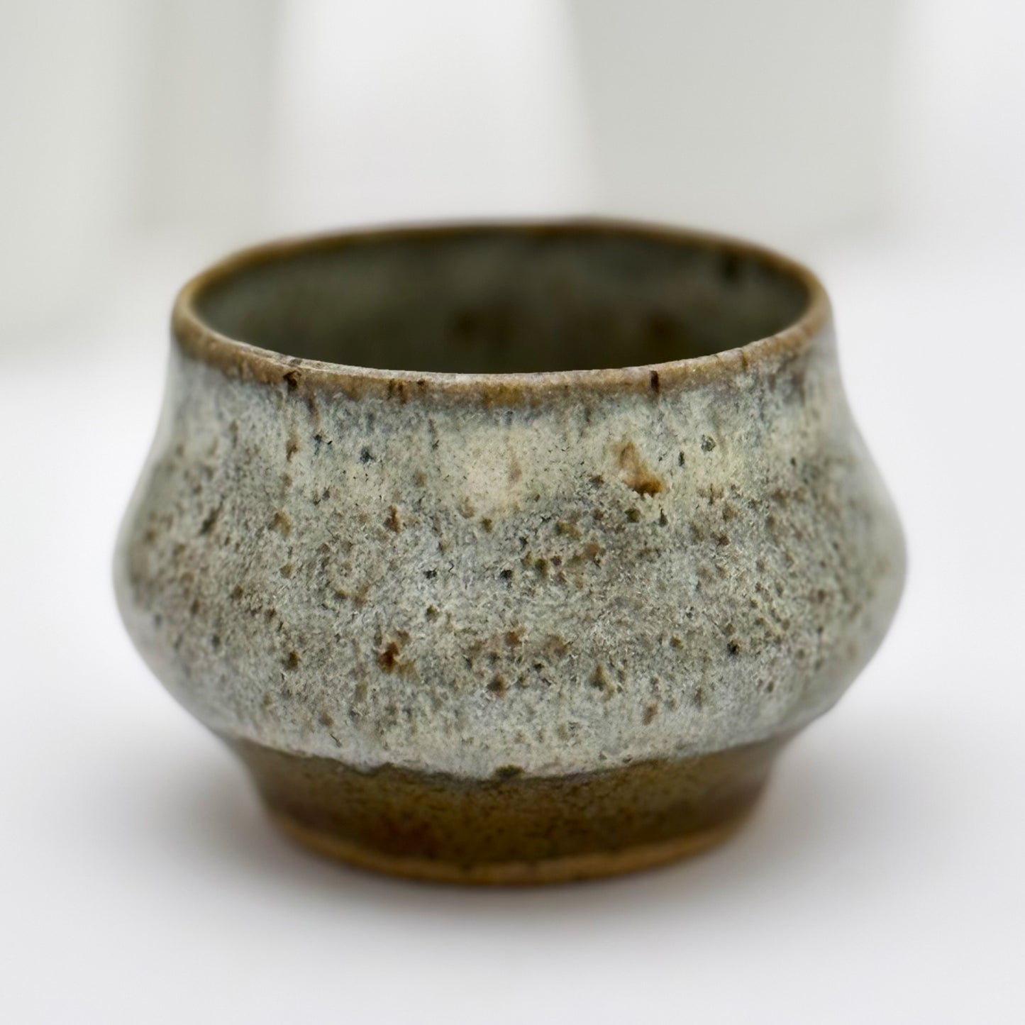 Ceramic pot with speckled glaze on a white background
