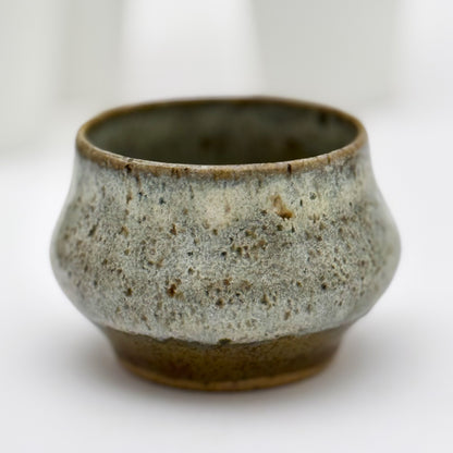 Ceramic pot with speckled glaze on a white background