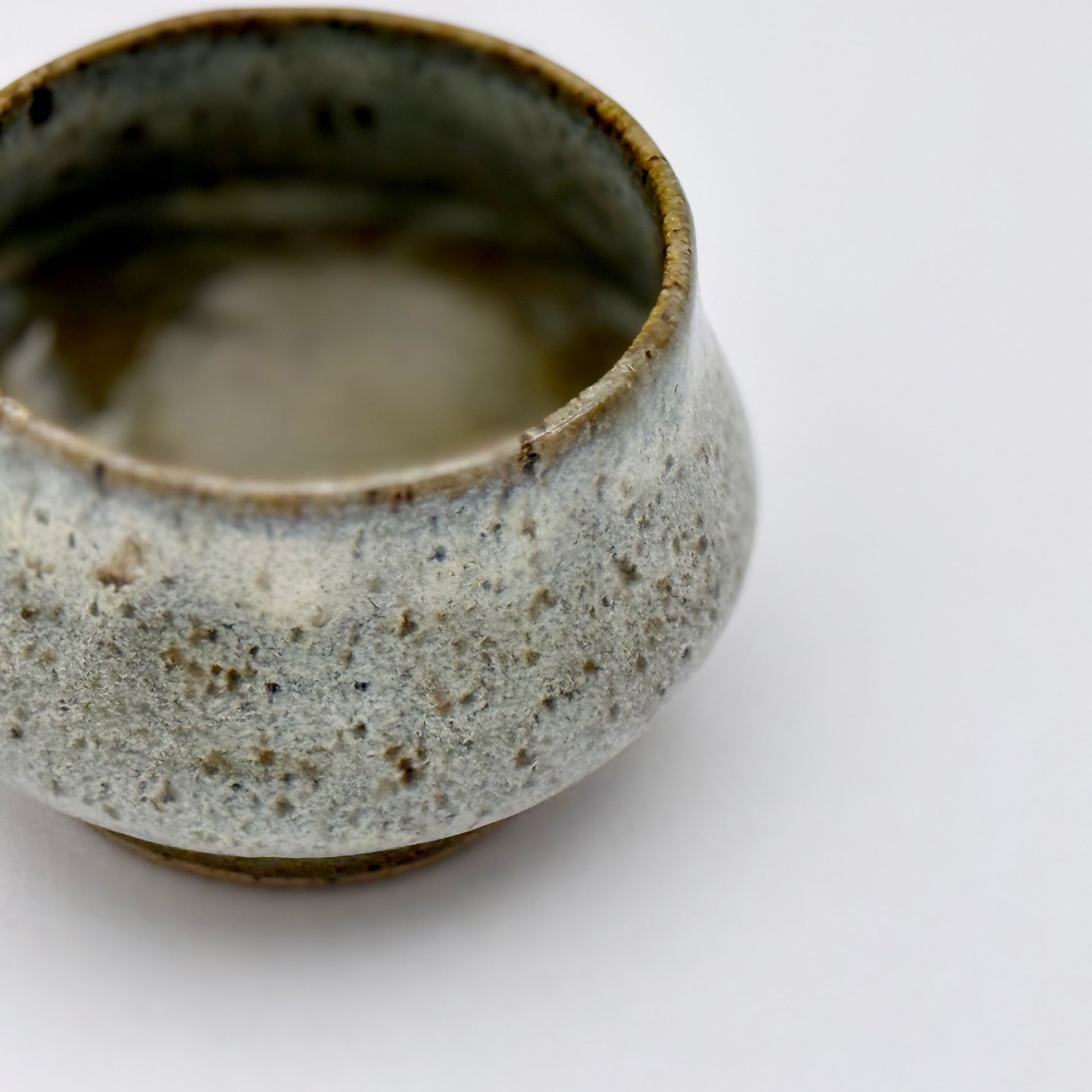 Ceramic pot with speckled glaze on a white background