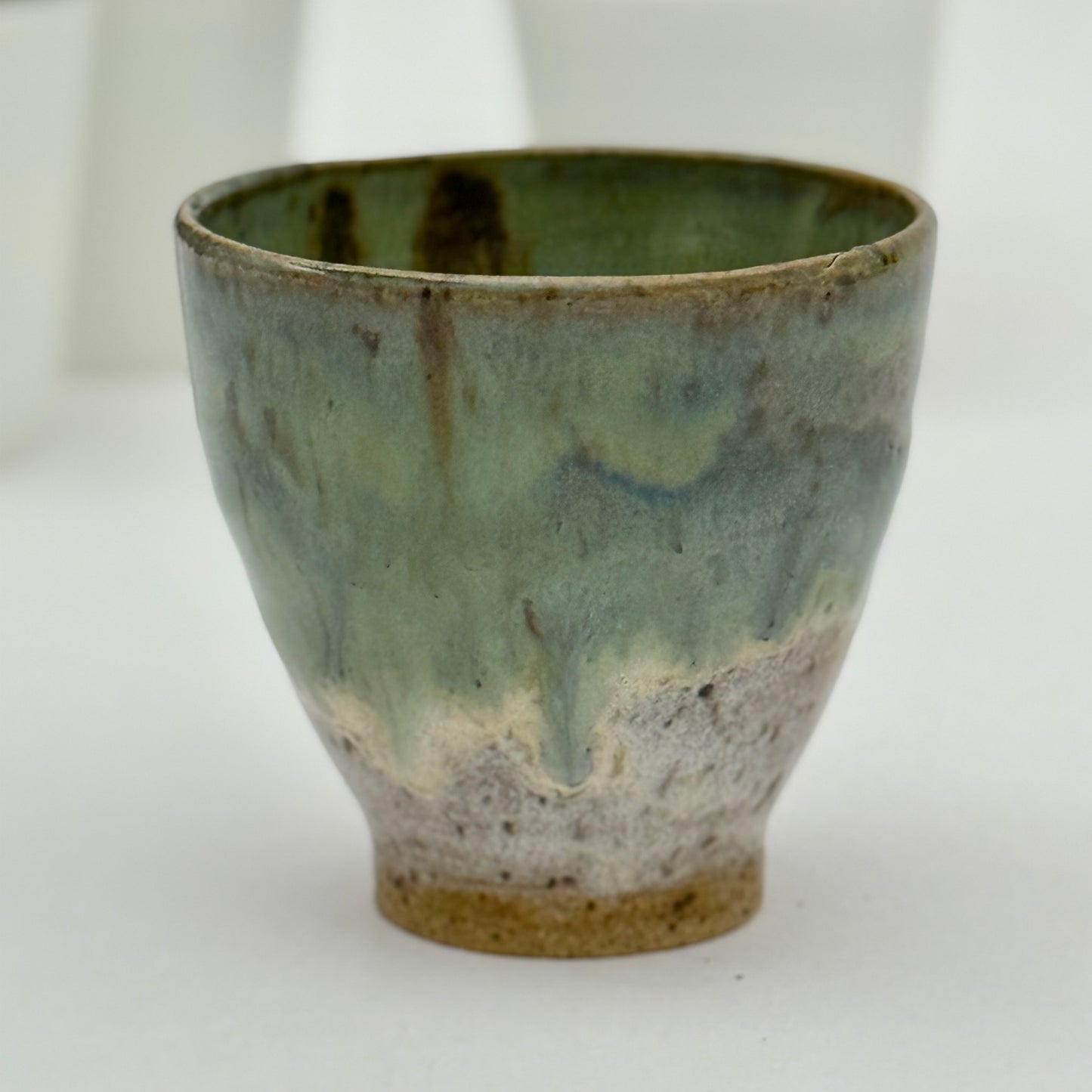 Green ceramic pot with a textured surface on a white background